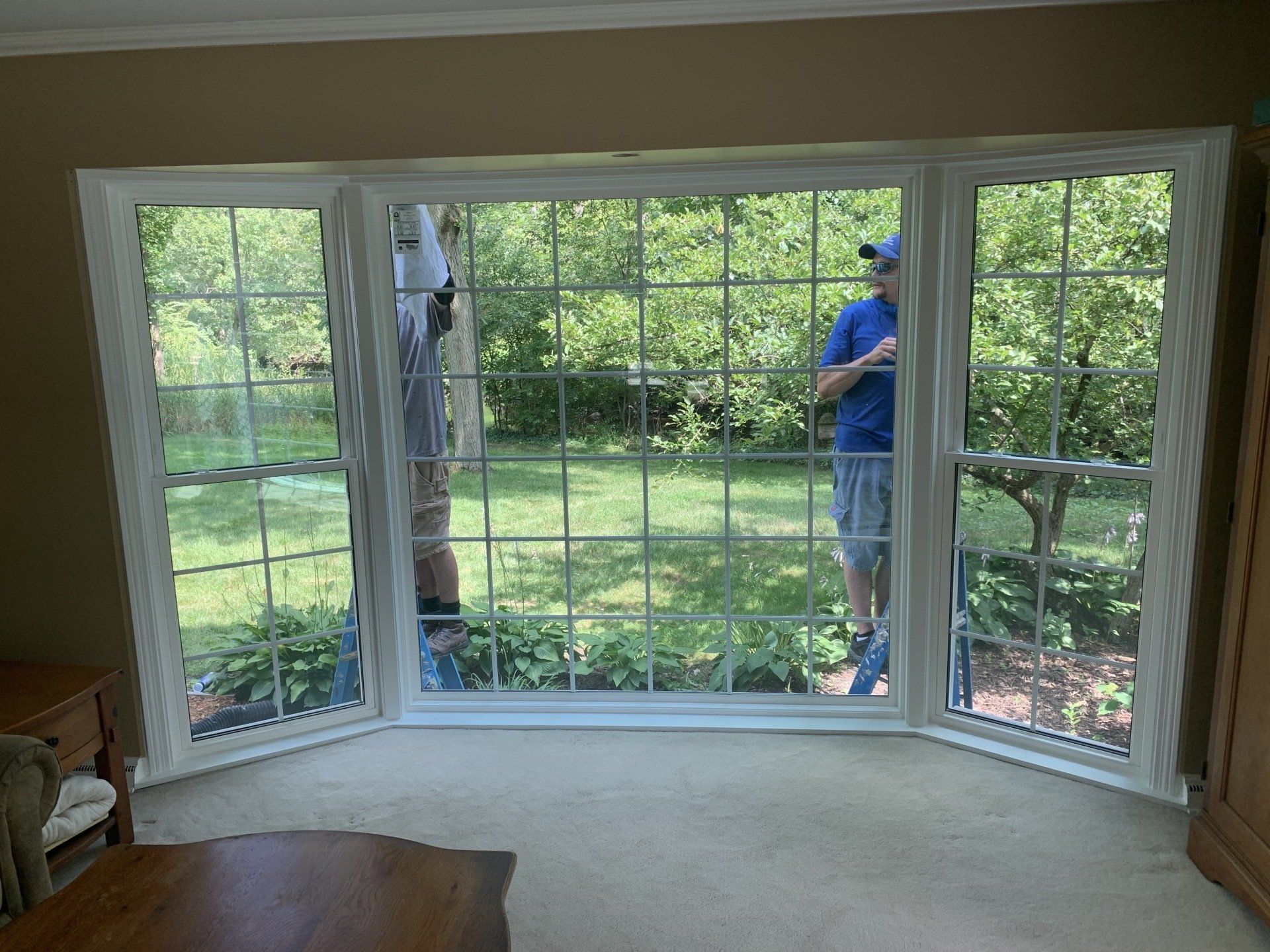 A man is standing in front of a large window in a living room.