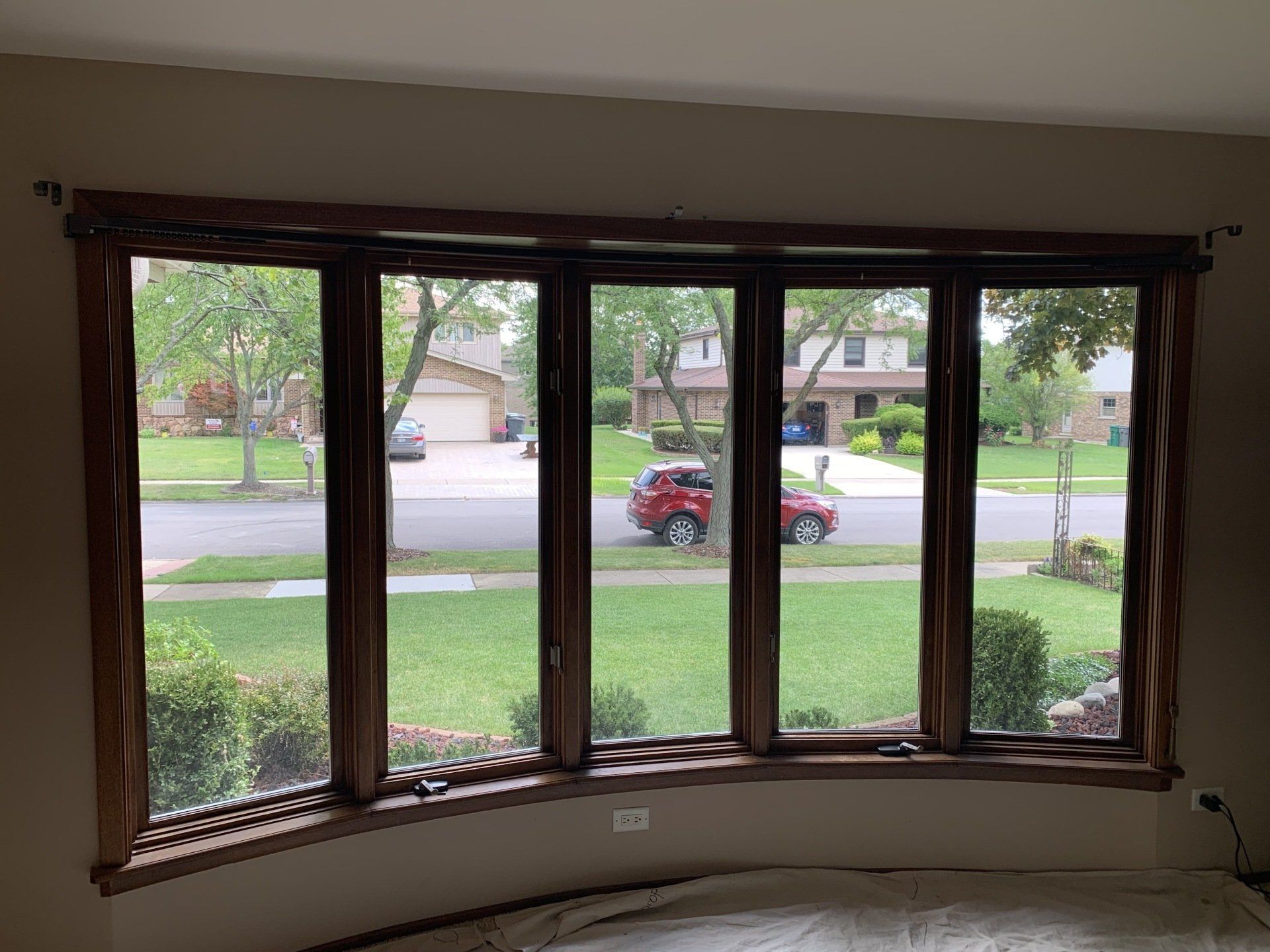A living room with a large bay window looking out to a residential street.