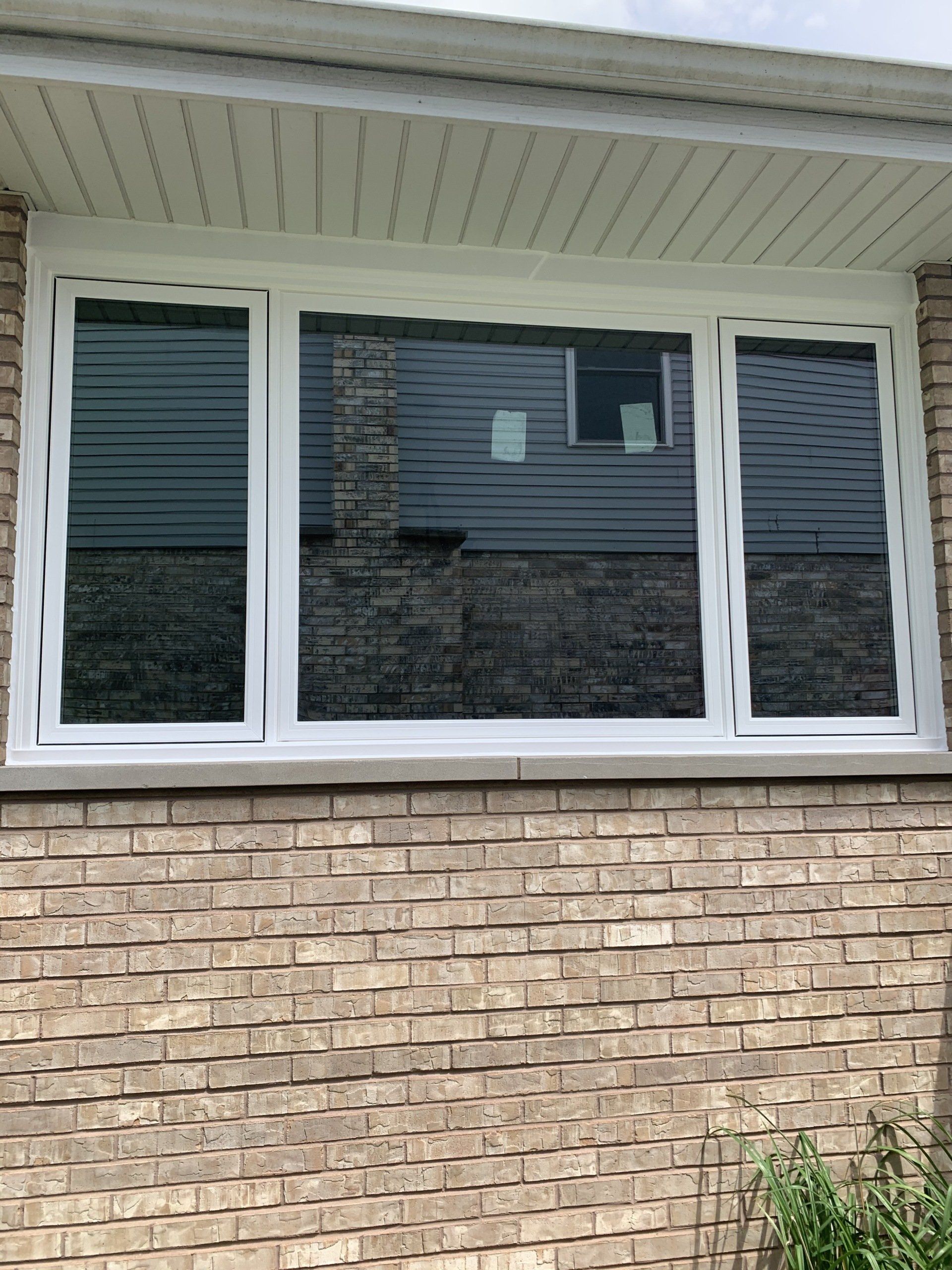 A brick building with three windows and a white frame.