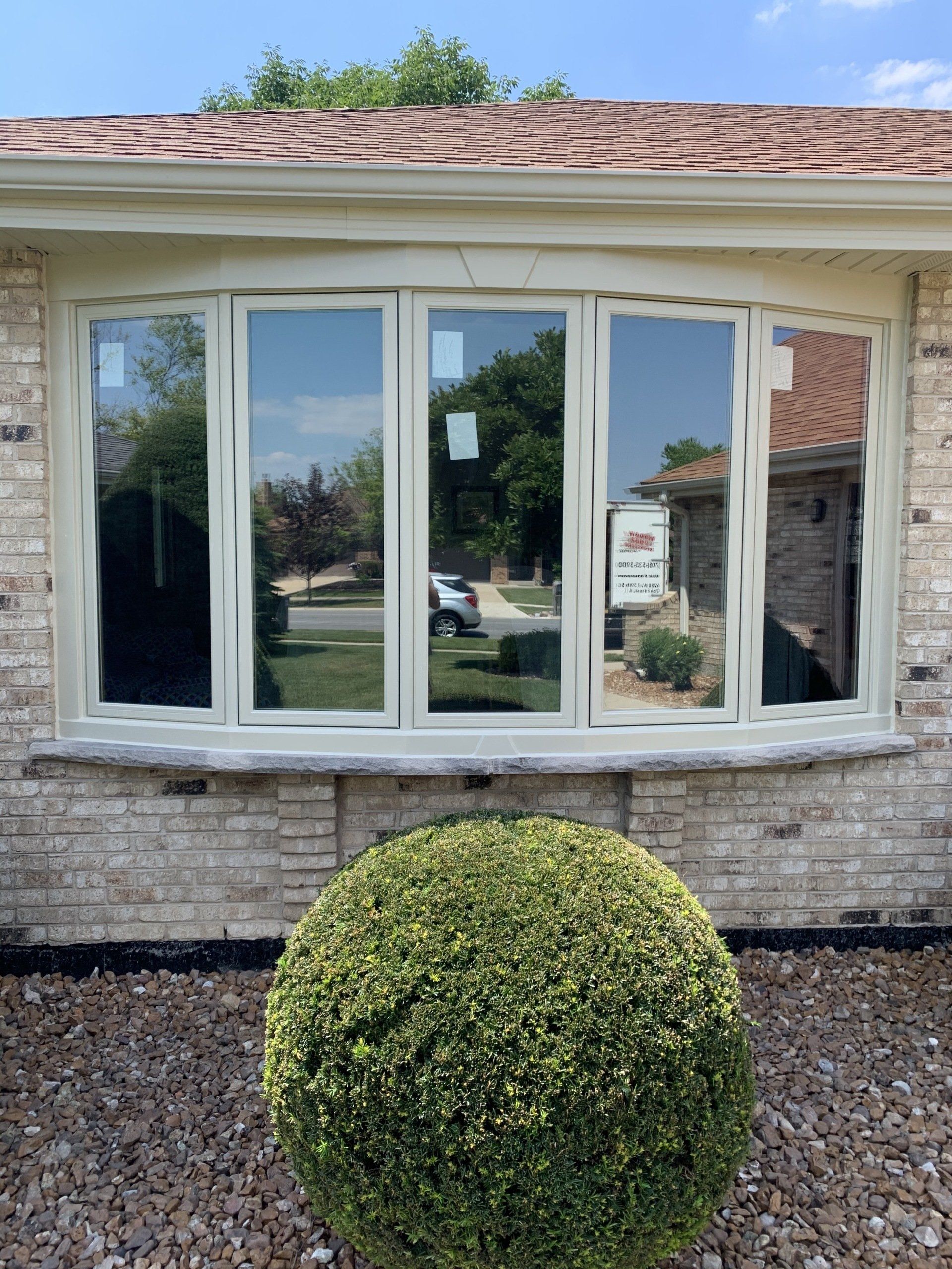 A house with a large window and a bush in front of it