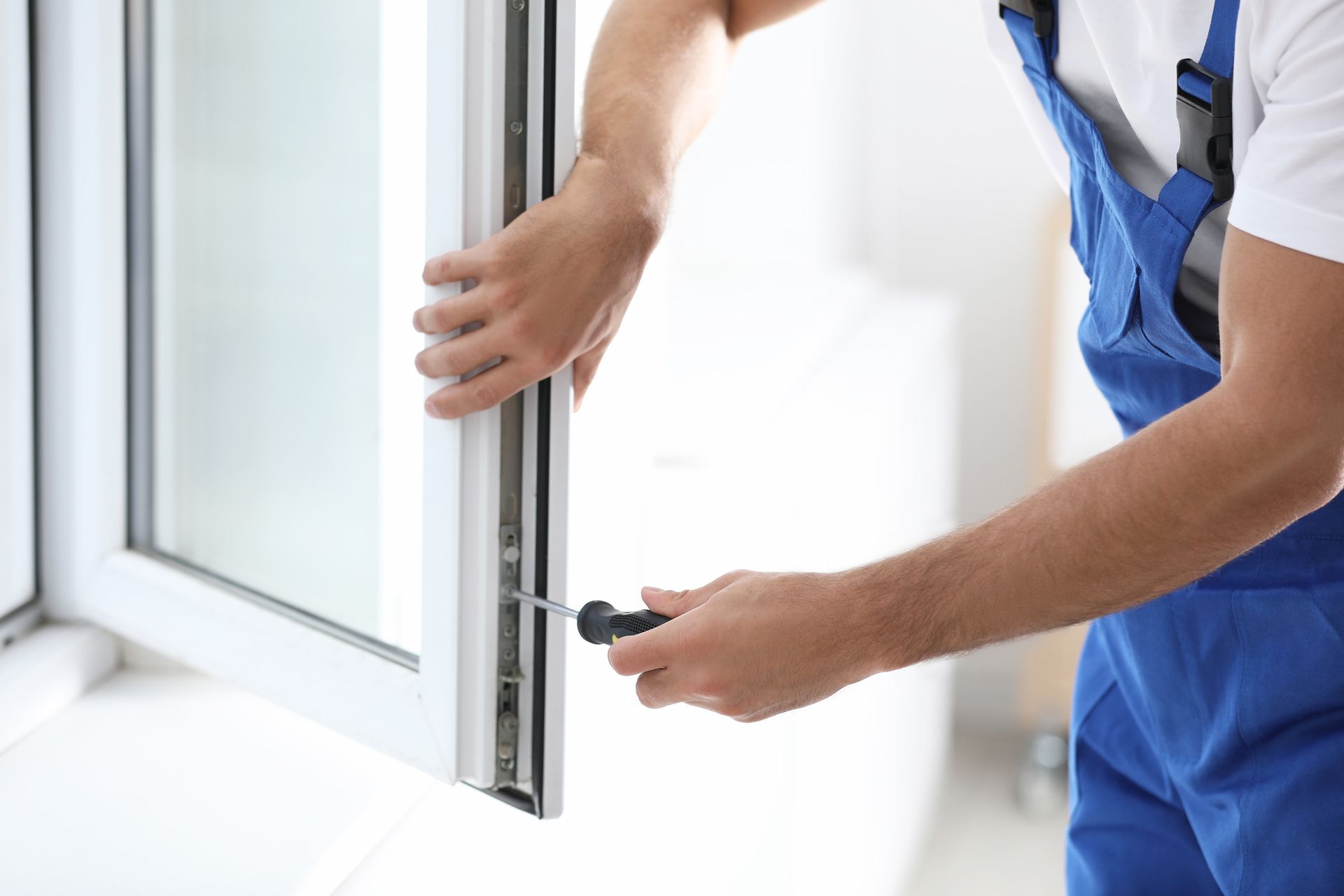 Worker installing plastic window indoors.