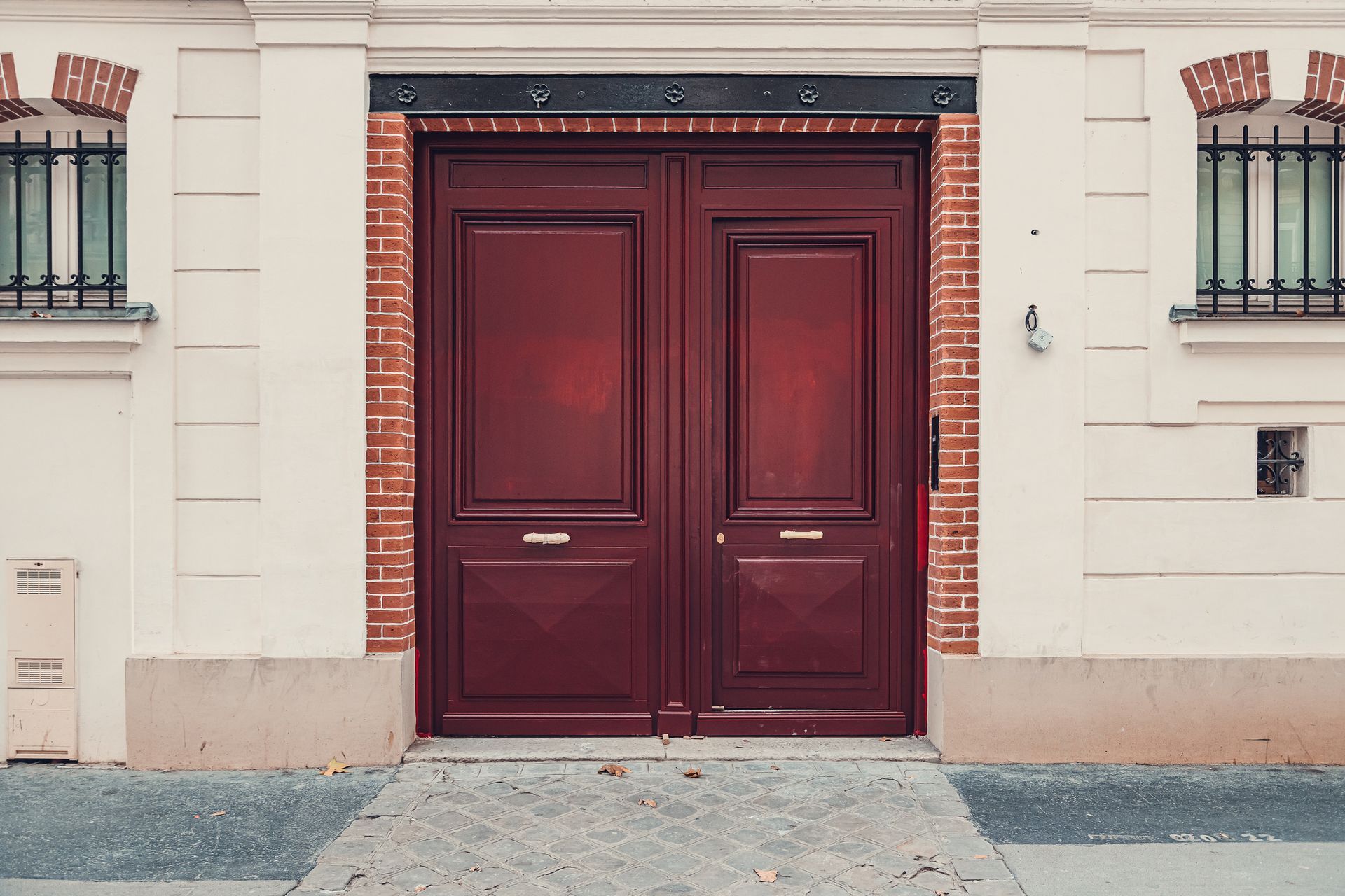 Red wooden double doors on a historic home showcasing expert entry door installation craftsmanship.