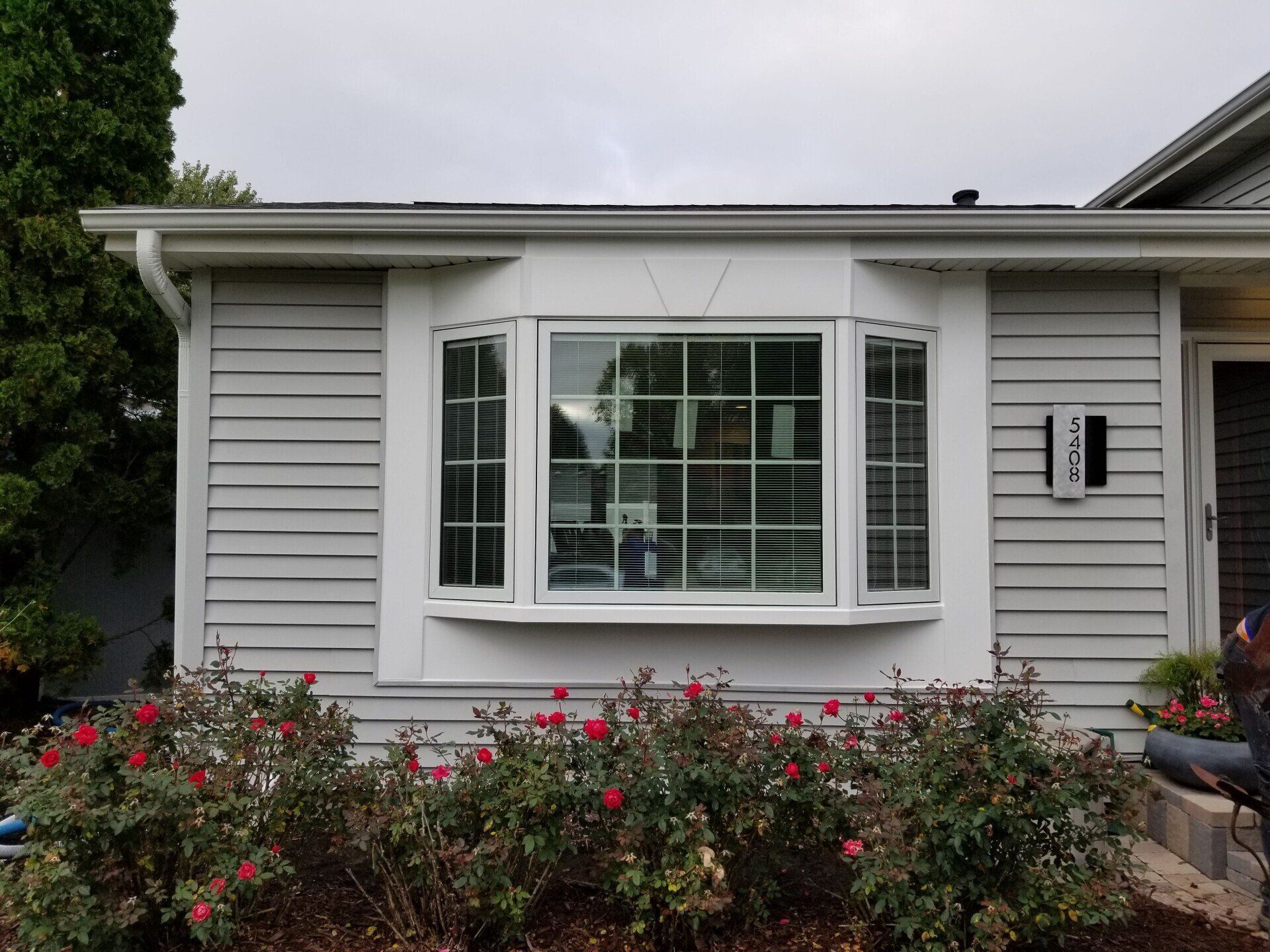 A white house with a large bay window and a mailbox in front of it.
