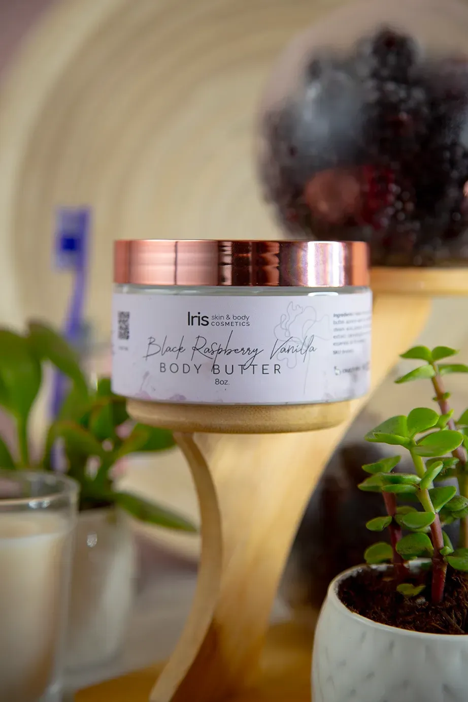 A jar of body butter is sitting on a wooden shelf next to a plant.