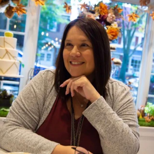 A woman is sitting in front of a window and smiling