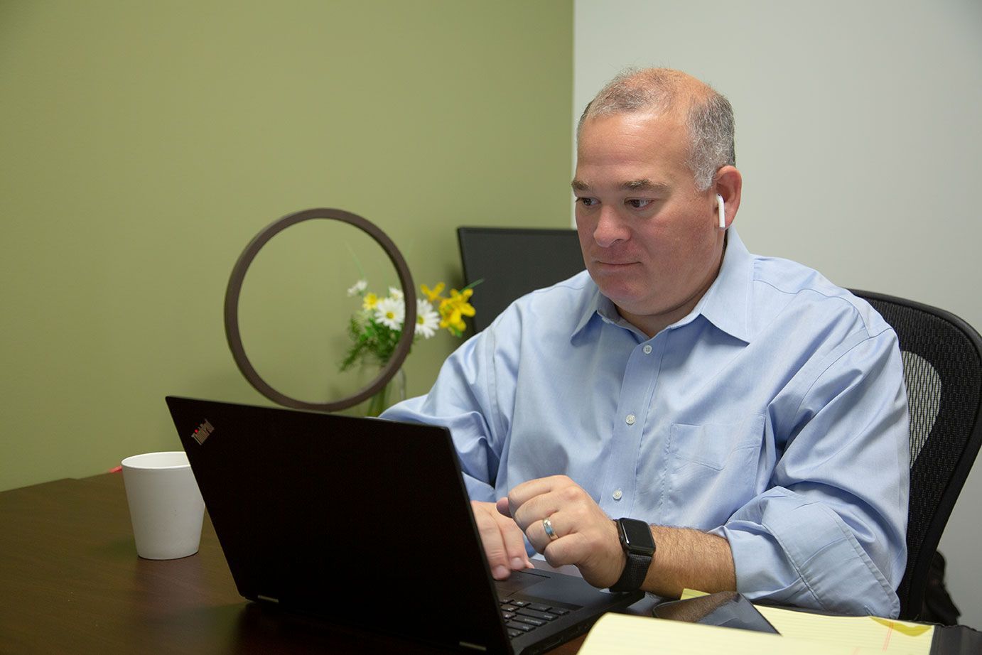 a man is sitting at a desk using a laptop computer .