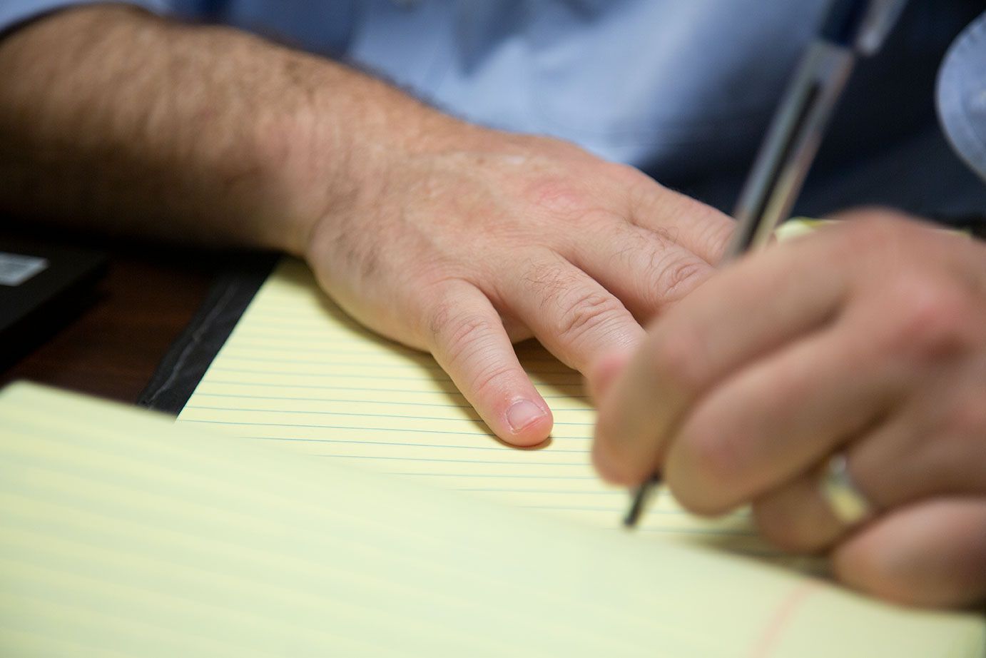 a man is writing on a piece of paper with a pen .