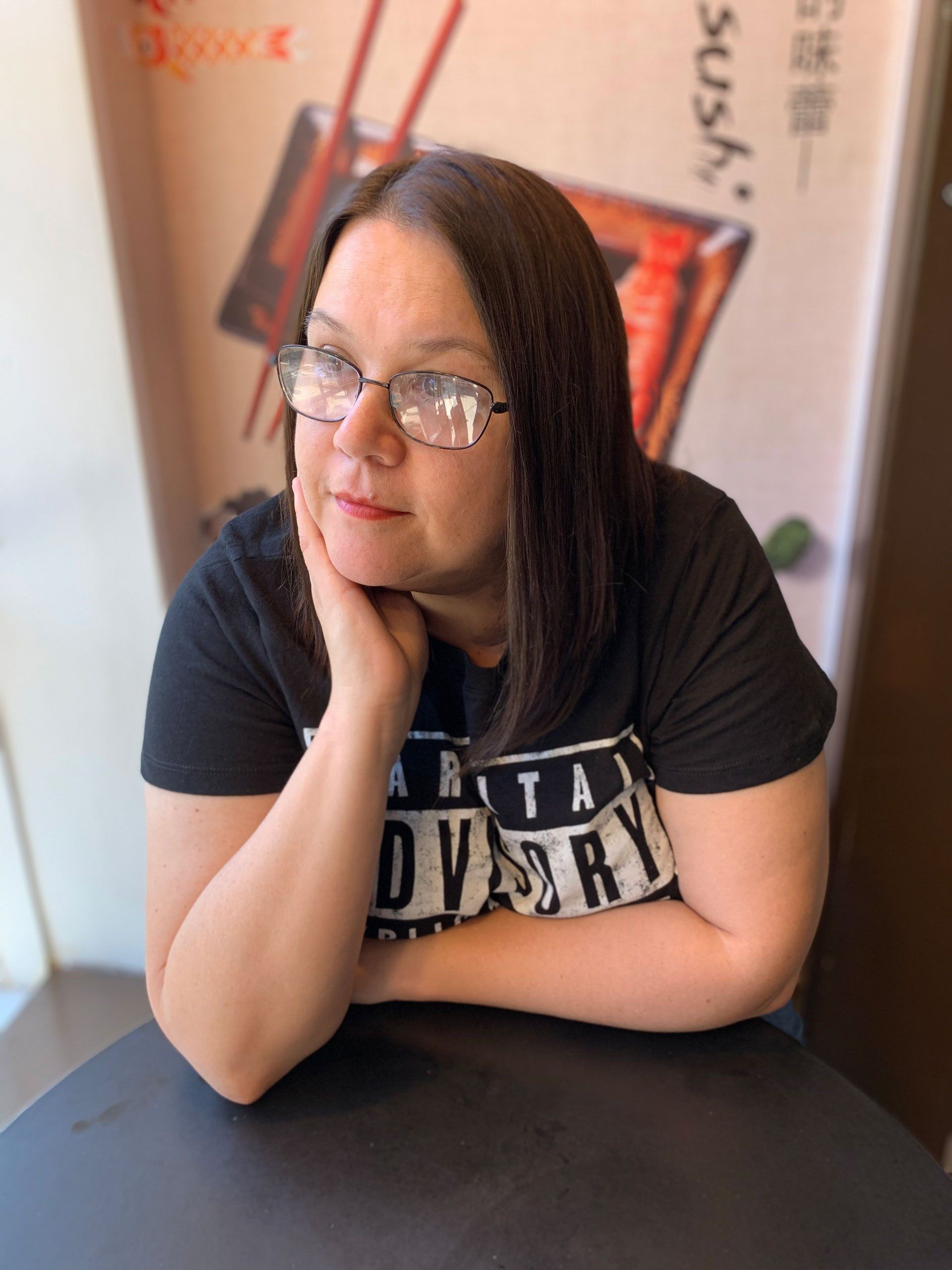 a woman wearing a shirt that says advisory is sitting at a table