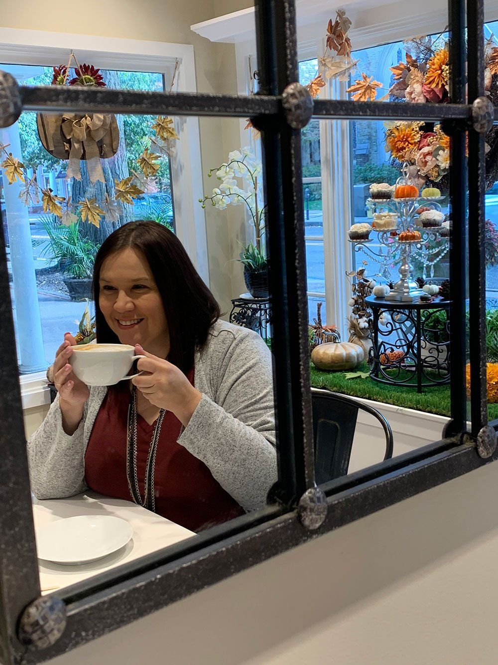 a woman is sitting at a table drinking a cup of coffee .