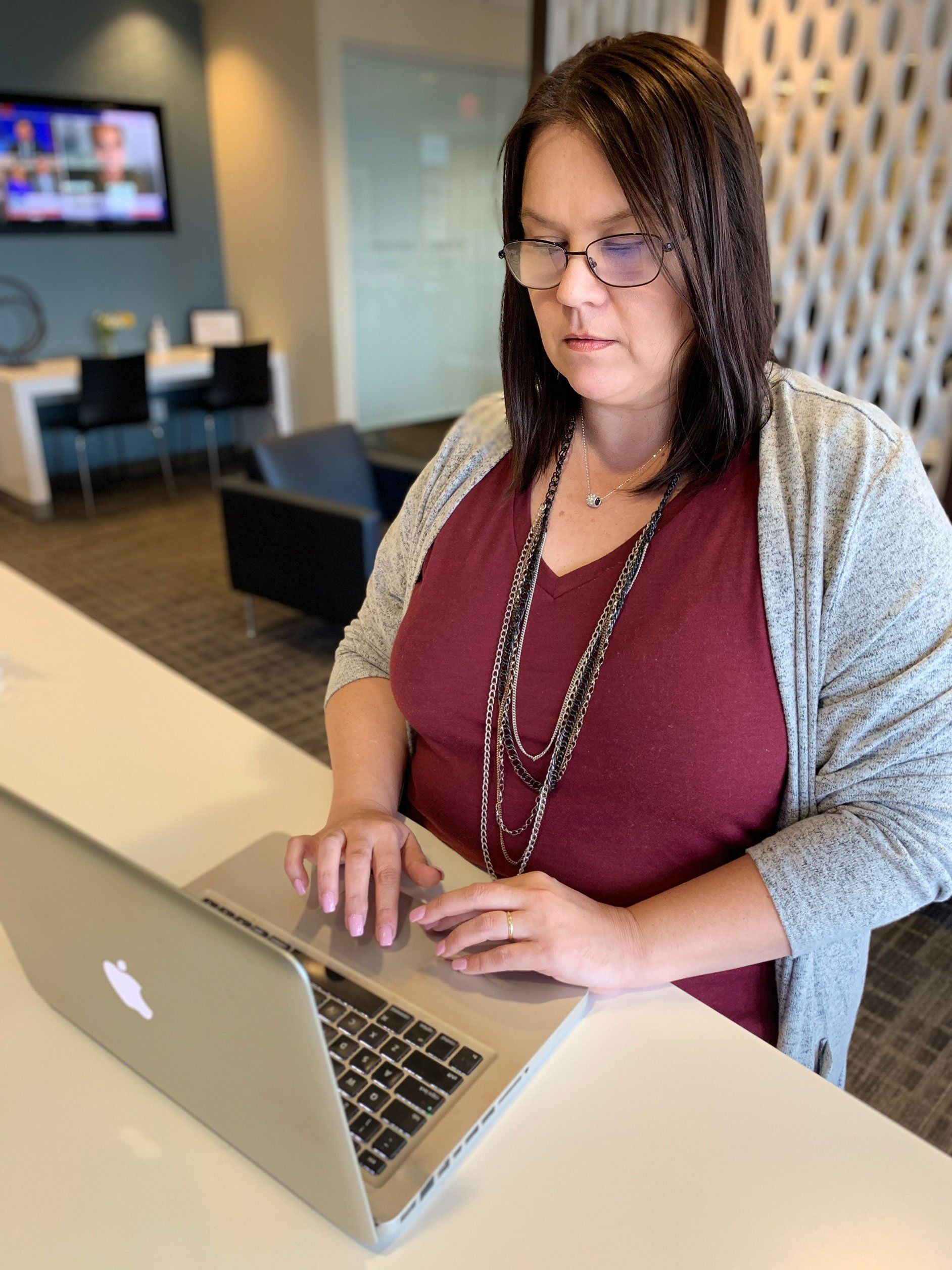 a woman wearing glasses is typing on a laptop computer .