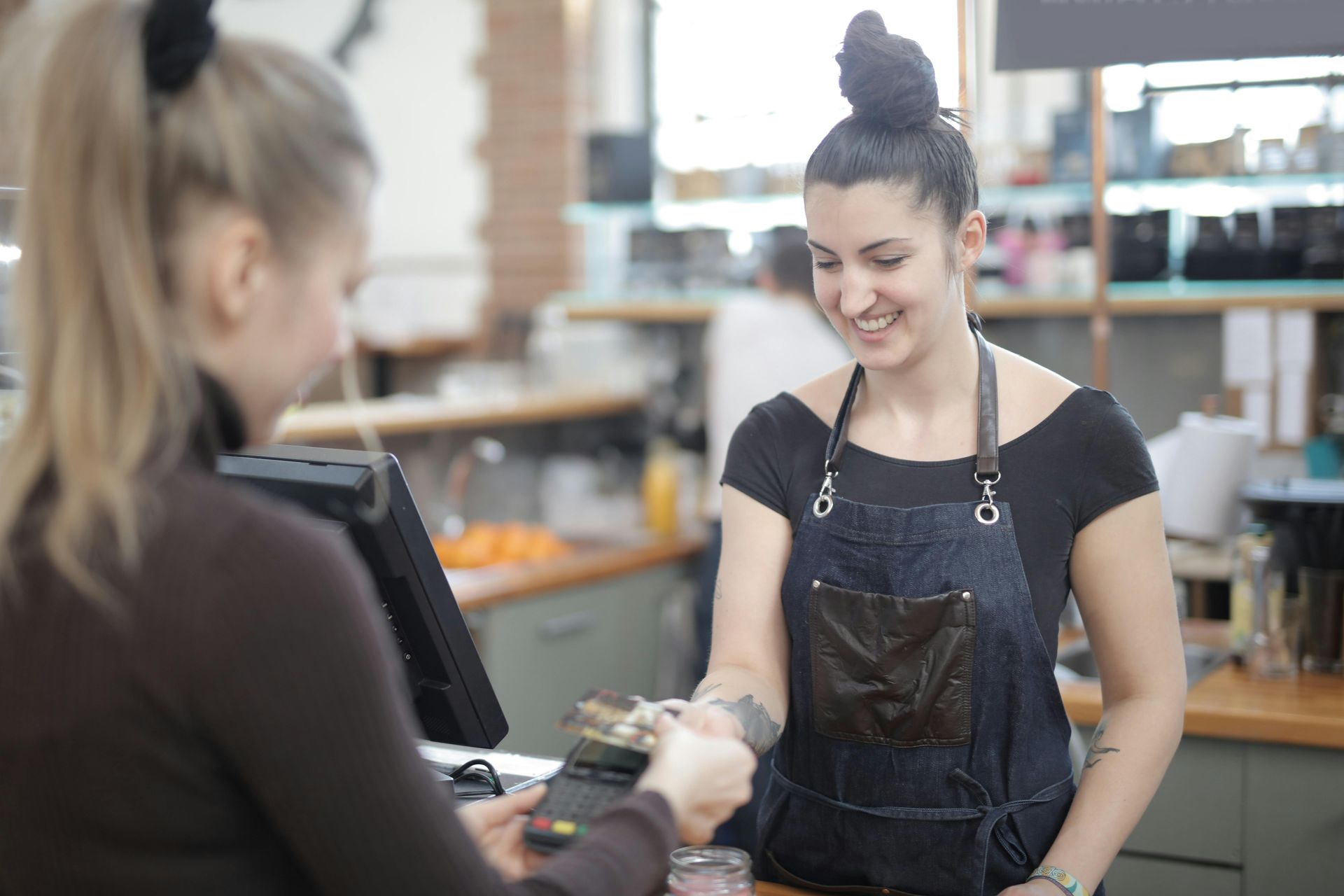 A woman is giving a credit card to another woman in a restaurant.