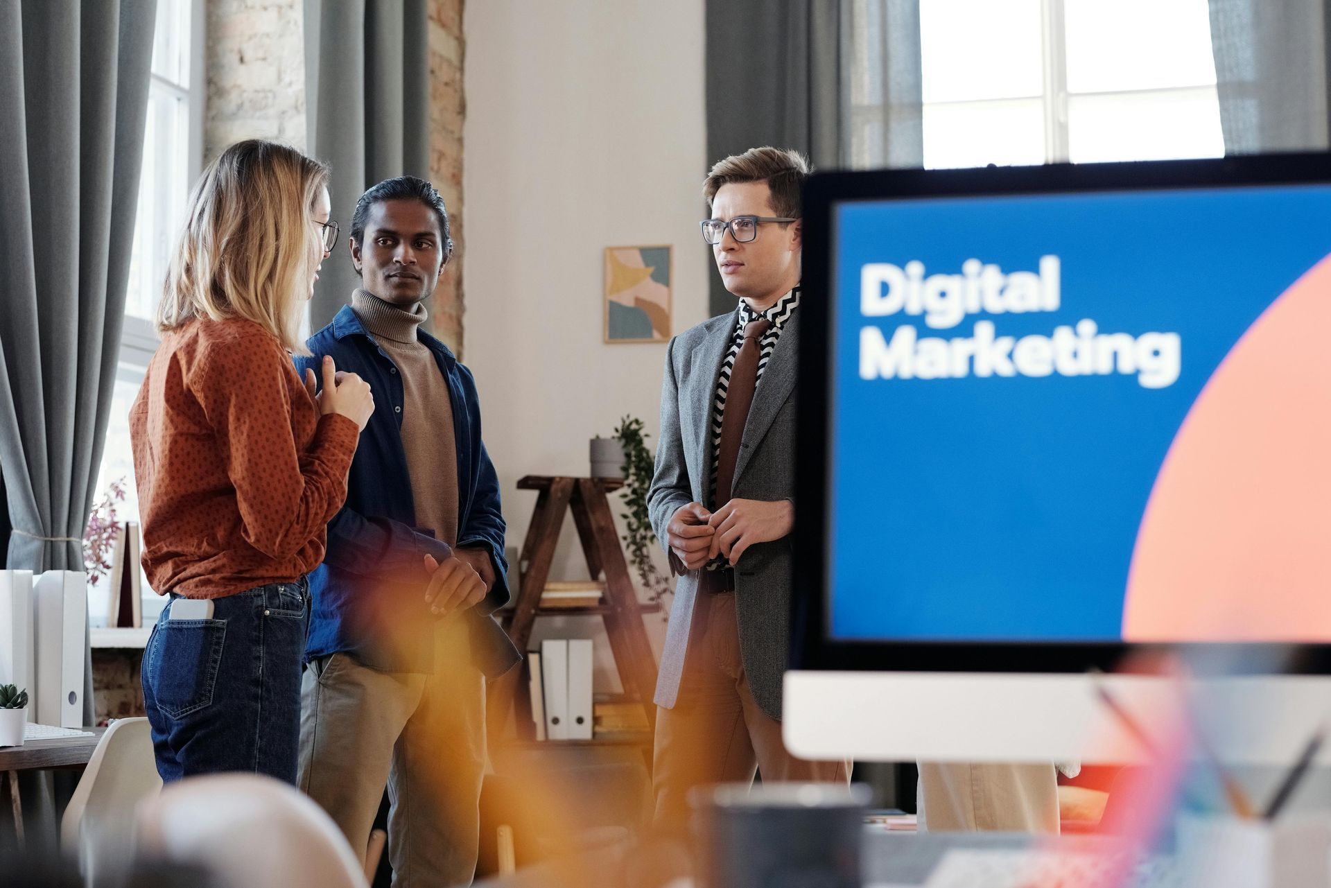 A group of people are standing in front of a computer screen that says digital marketing.