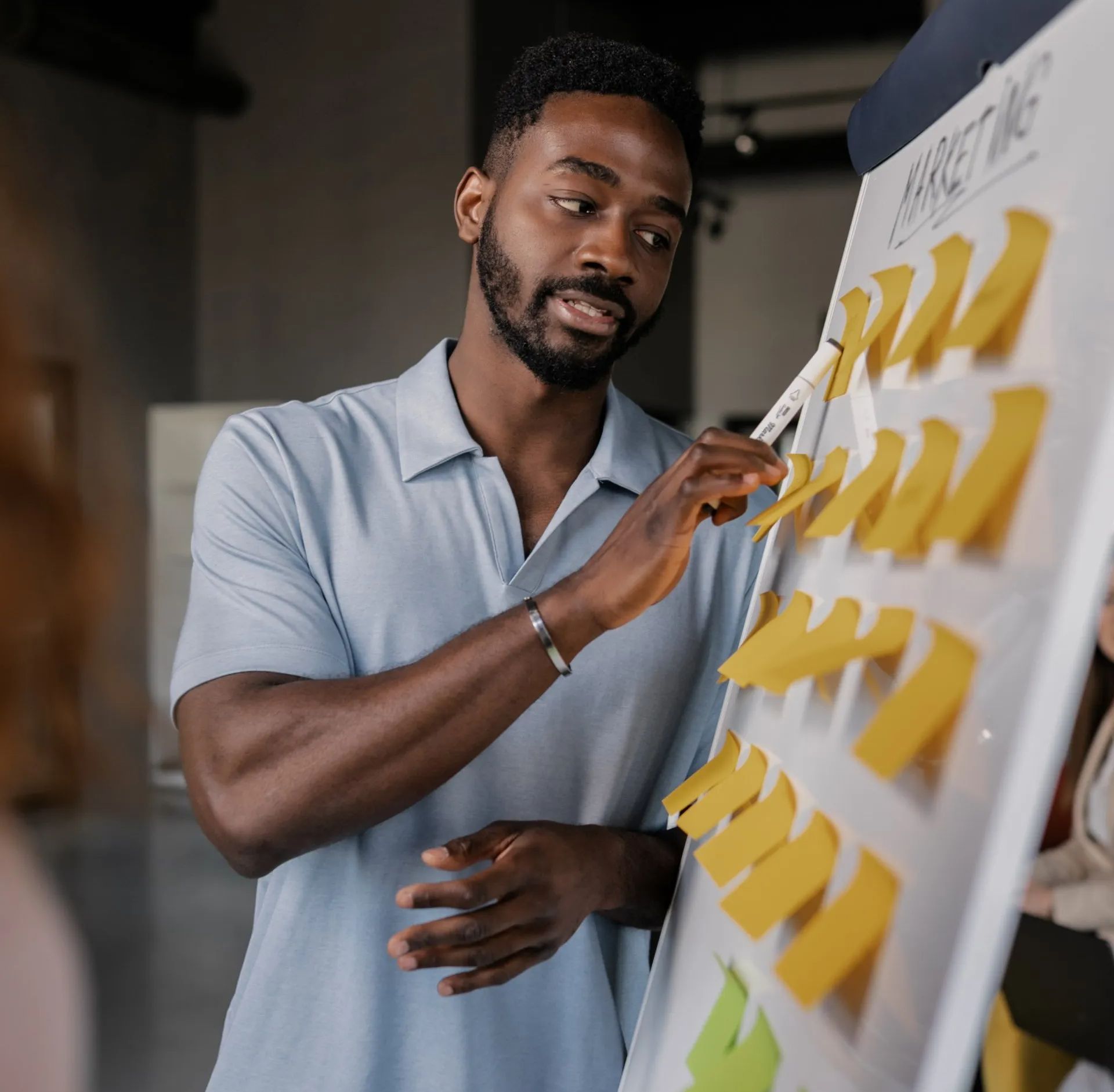 A man is standing in front of a white board with sticky notes on it.