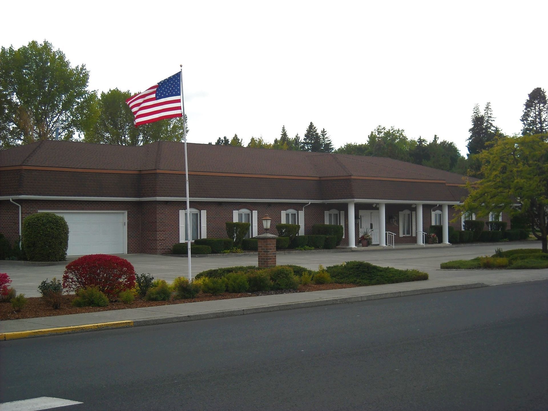 Building with an American flag in front, brick exterior, trees in the background.