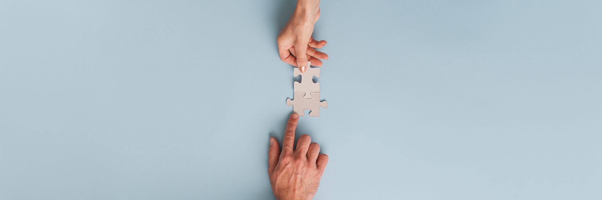 A person is putting a puzzle piece into another person 's hand.
