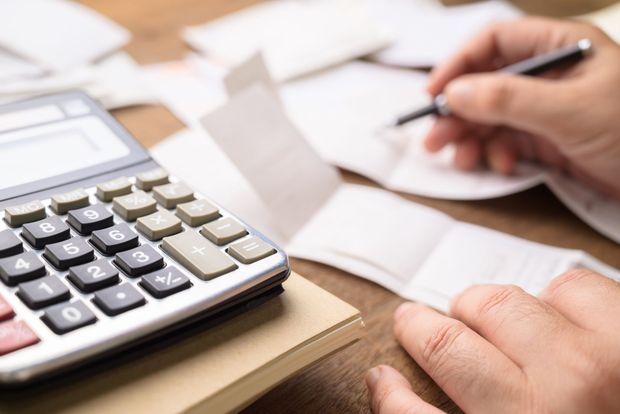 A person is using a calculator and writing on a piece of paper.