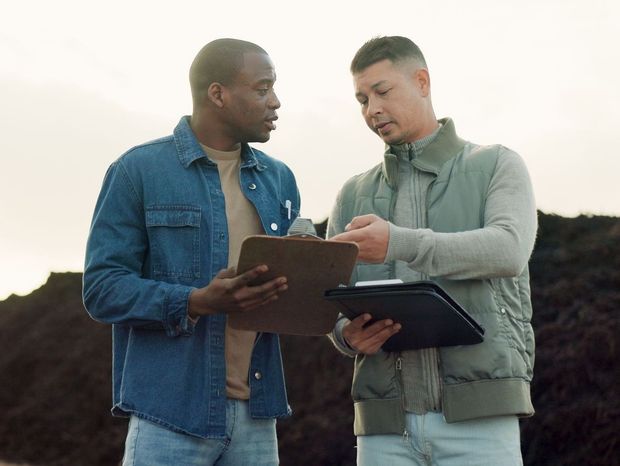 Two men are standing next to each other looking at a clipboard.