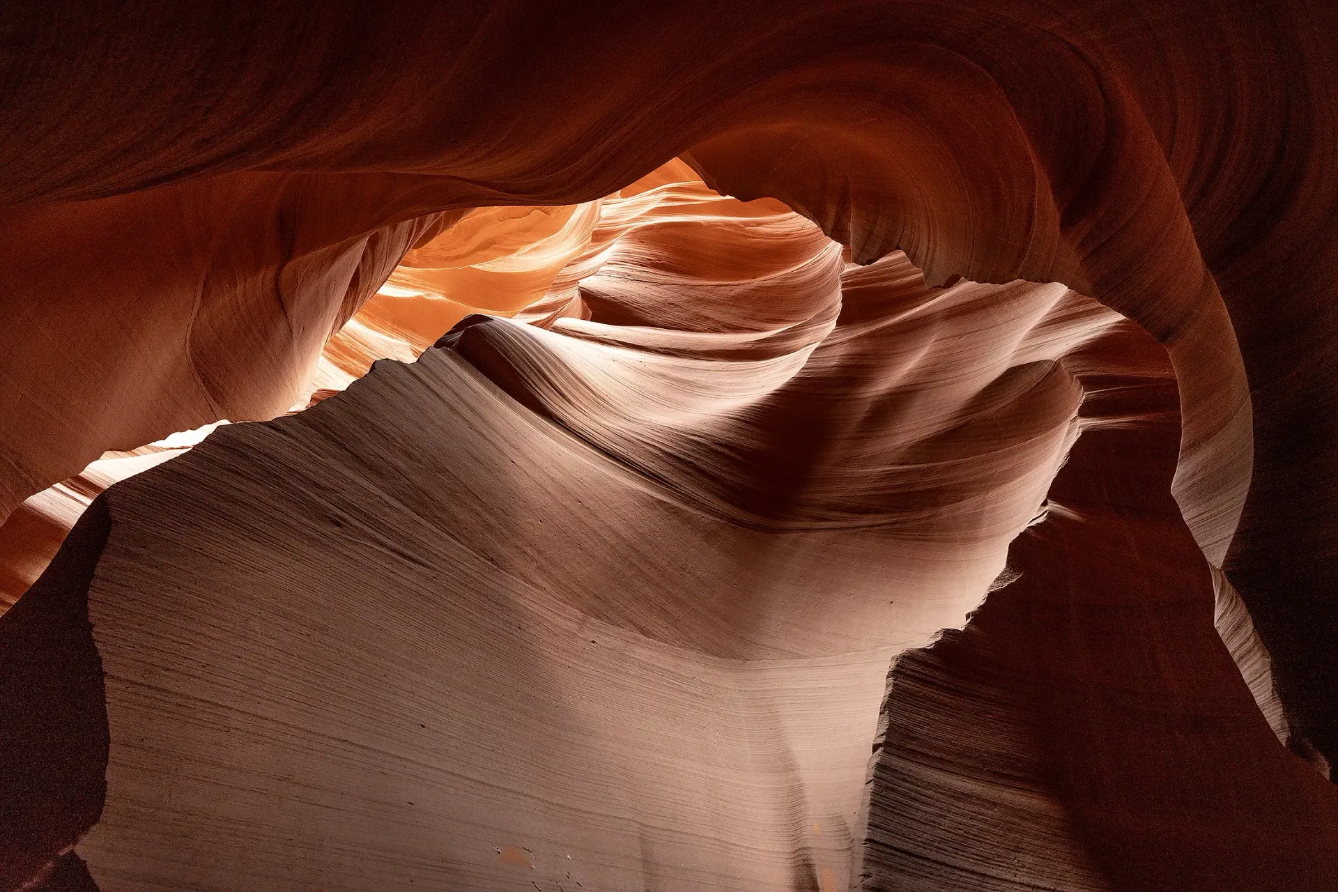 Sunlit sandstone canyon walls with swirling curves and warm orange-brown tones