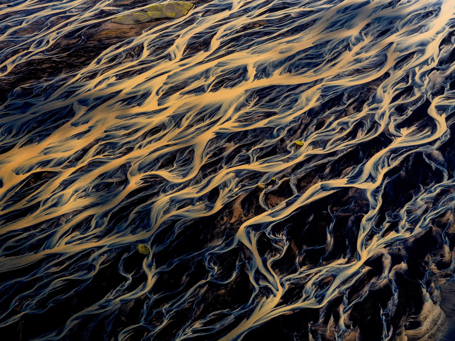 Golden ripples of water over a dark surface, forming a textured abstract pattern
