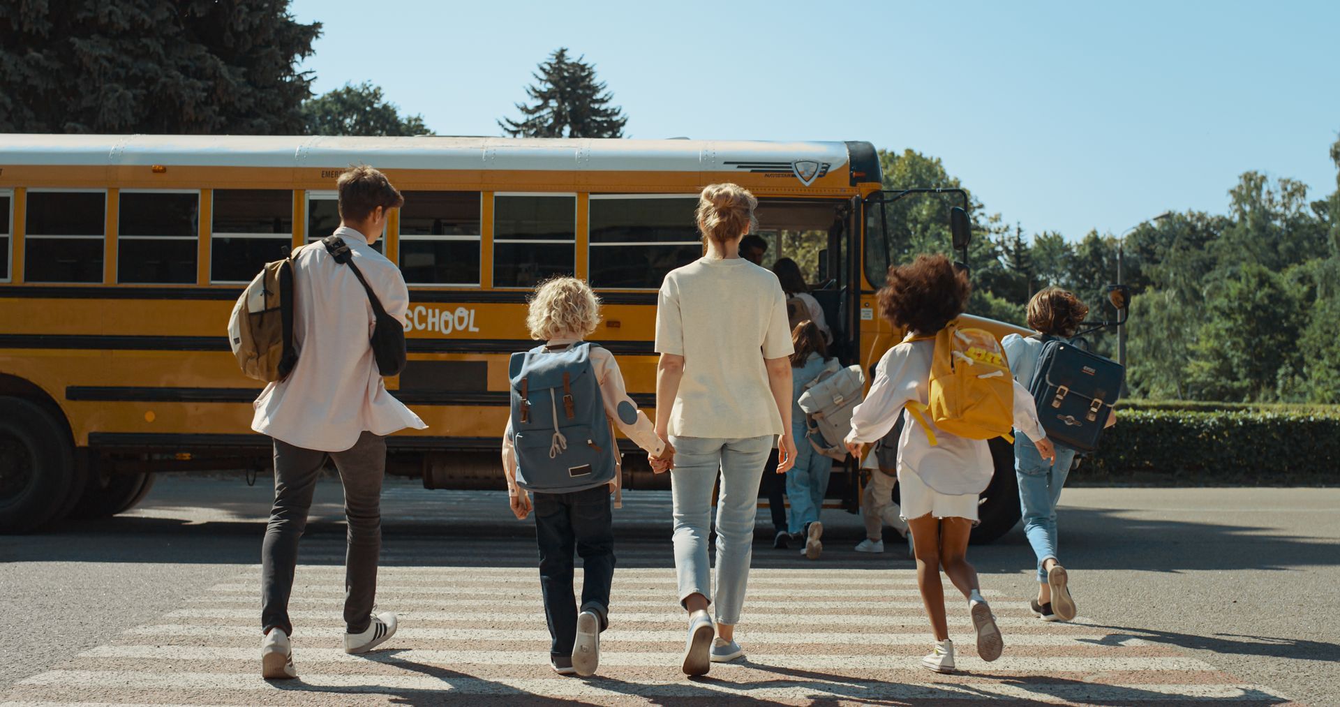 A group of children are walking towards a school bus.