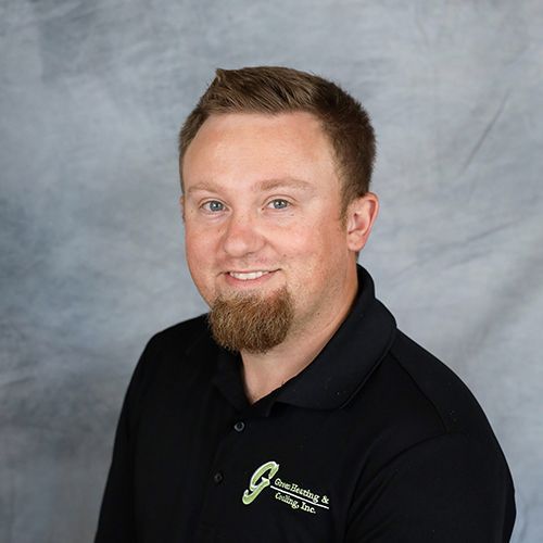 Man with short brown hair and beard, wearing a black polo shirt, smiling.