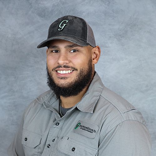 Man in gray cap and shirt, smiling, with a full beard.
