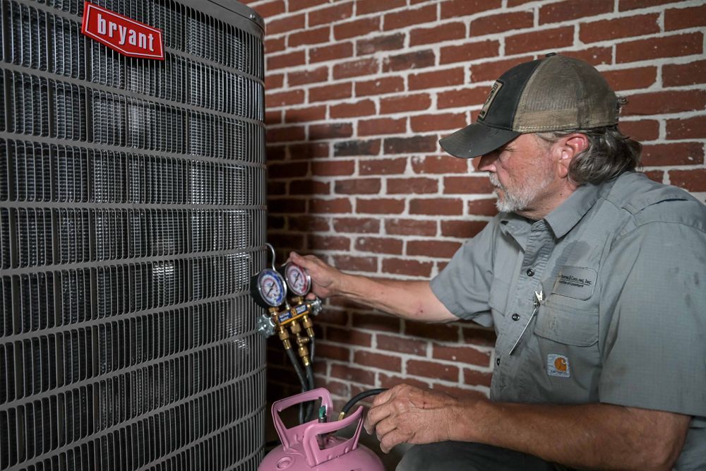 HVAC technician servicing a Bryant air conditioning unit on a brick wall.