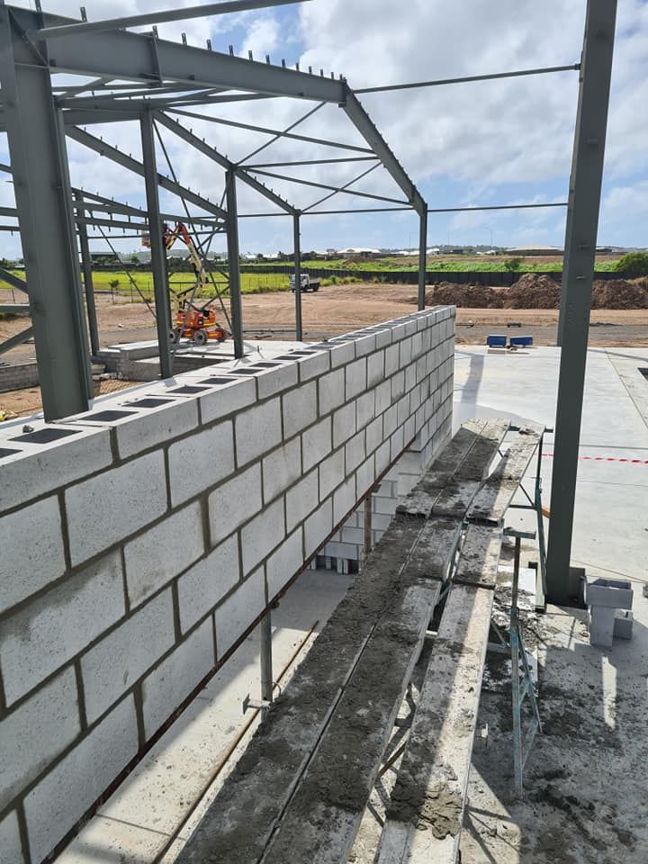 A Brick Wall Is Being Built On The Side Of A Building — CQBB Concreting Pumping Pty Ltd In Barmaryee, QLD