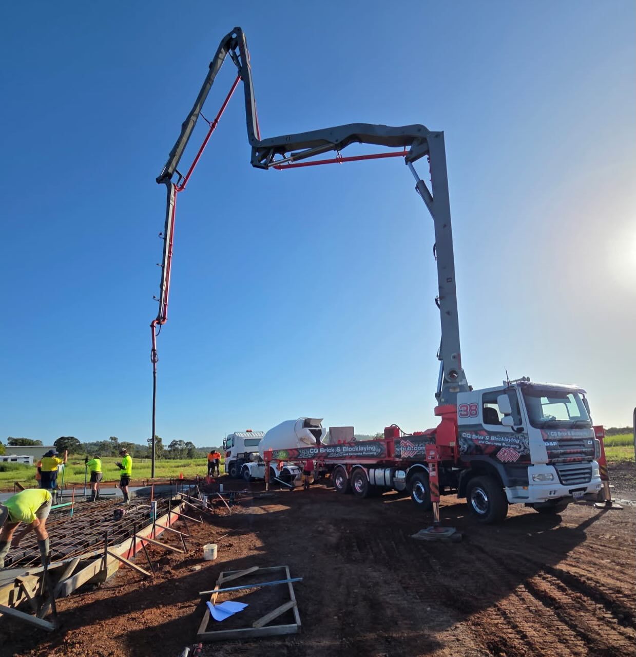 A Crane Is Pouring Concrete On A Construction Site At Sunset — CQBB Concreting Pumping Pty Ltd In Barmaryee, QLD