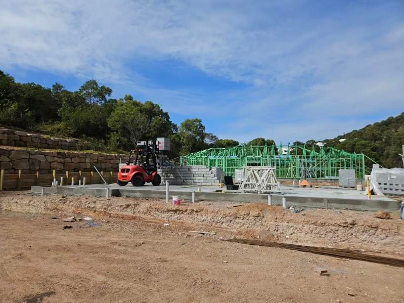 A Red Forklift Is Parked In Front Of A Building Under Construction — CQBB Concreting Pumping Pty Ltd In Barmaryee, QLD