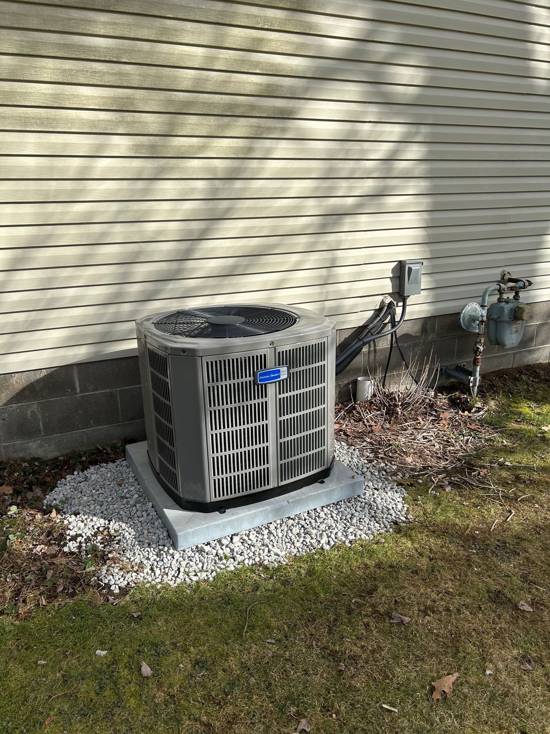 Air conditioning unit outside a house on a gravel base.