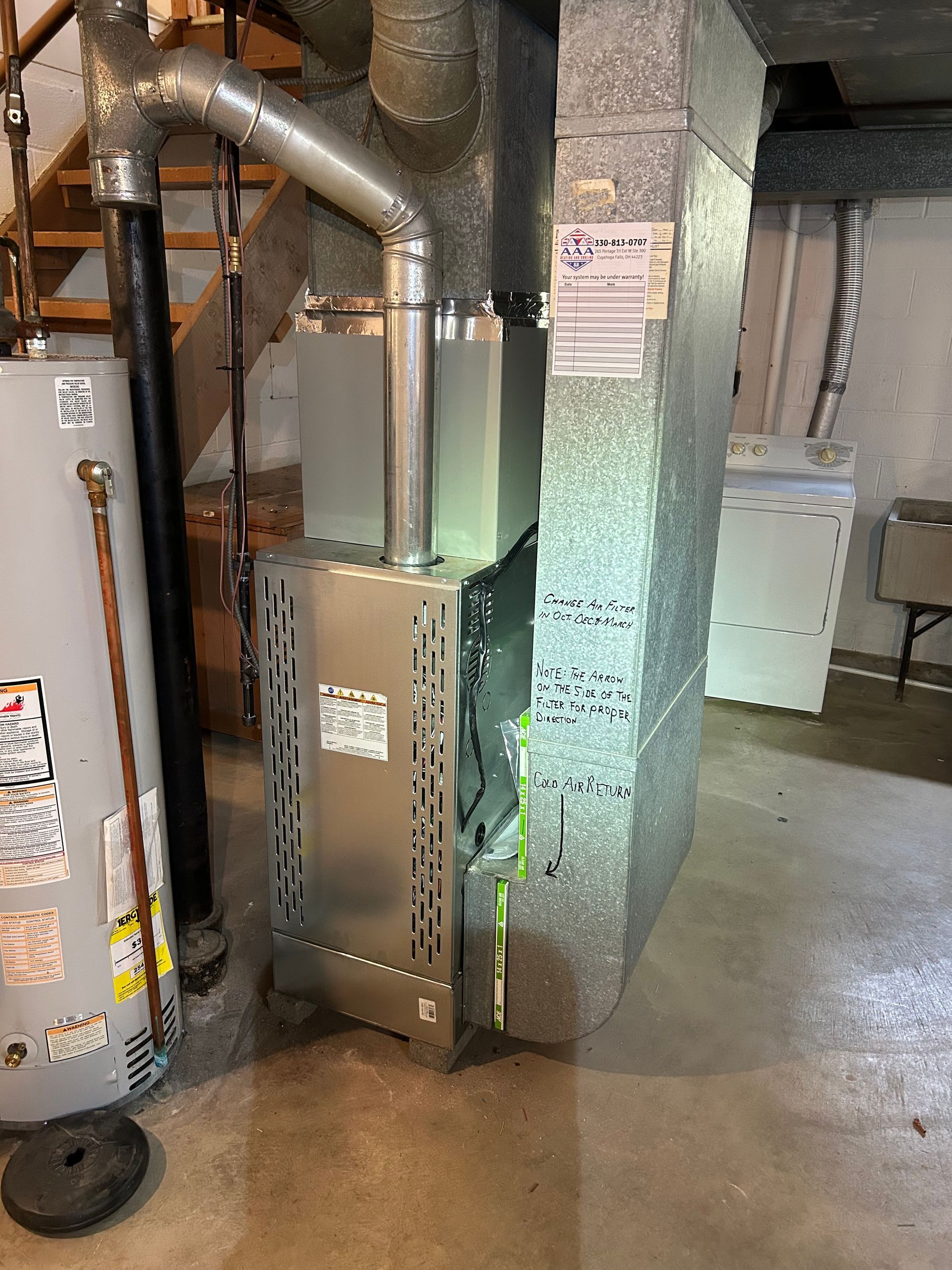 Furnace and hot water heater in a basement setting. Staircase visible.