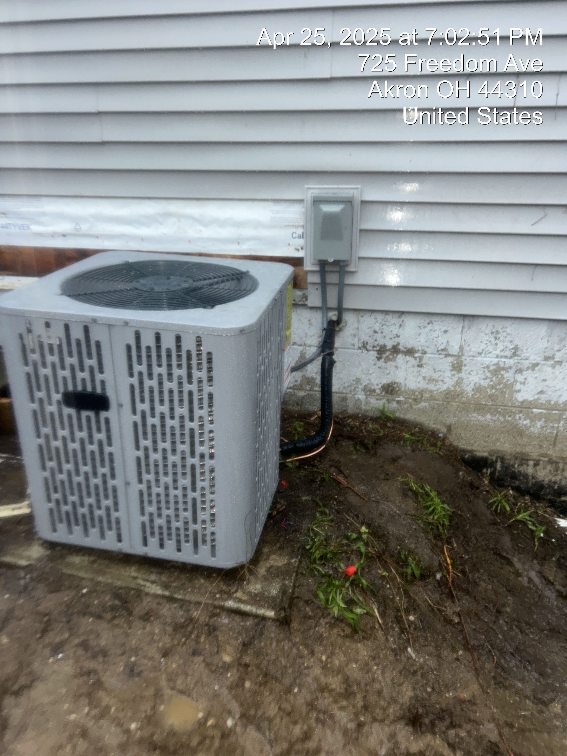 Air conditioner unit next to a house with electrical box.