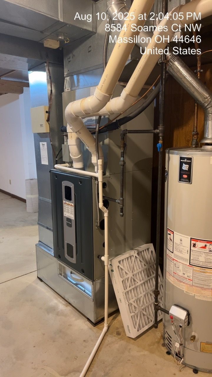Furnace and water heater in a utility room. Filter is removed, various pipes visible.