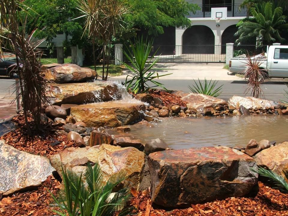 A white truck is parked in front of a house with a waterfall in the background