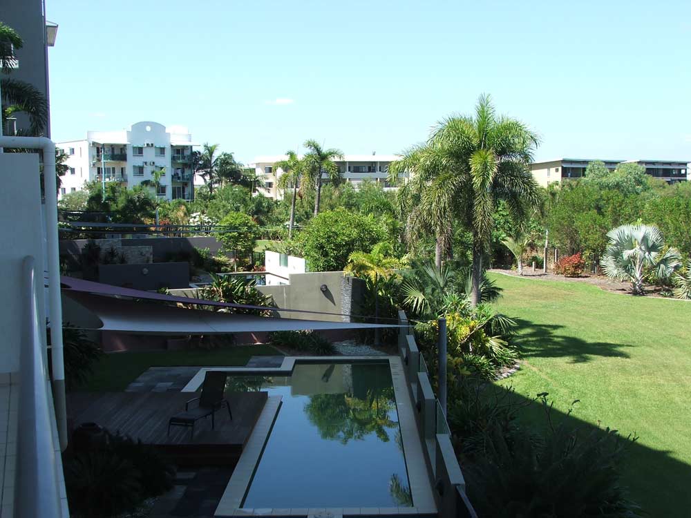 outdoor landscape with trees and grass next to buildings