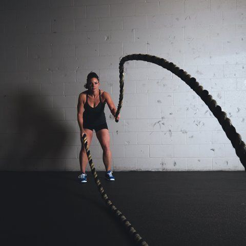 A woman is doing a battle ropes exercise