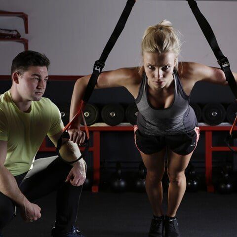 A woman is doing push ups while a man watches