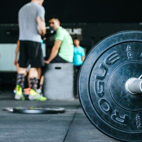 A rogue barbell is sitting on the floor in a gym
