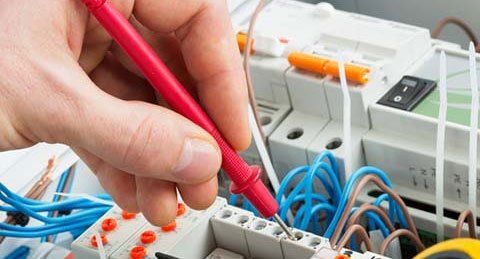 A person is using a multimeter to test a circuit board.