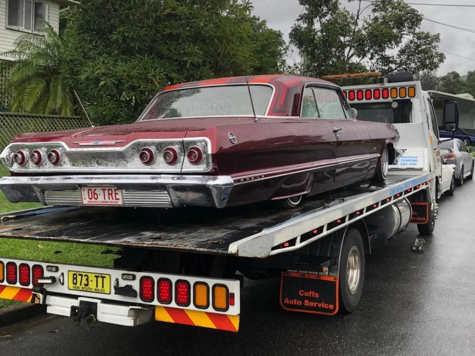 A Red Car is Being Towed by a Tow Truck — Coffs Tow Trucks In North Boambee Valley, NSW