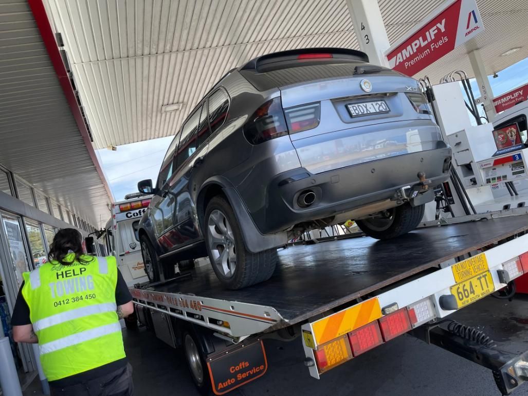 A Car is Being Towed by a Tow Truck at a Gas Station — Coffs Tow Trucks In North Boambee Valley, NSW