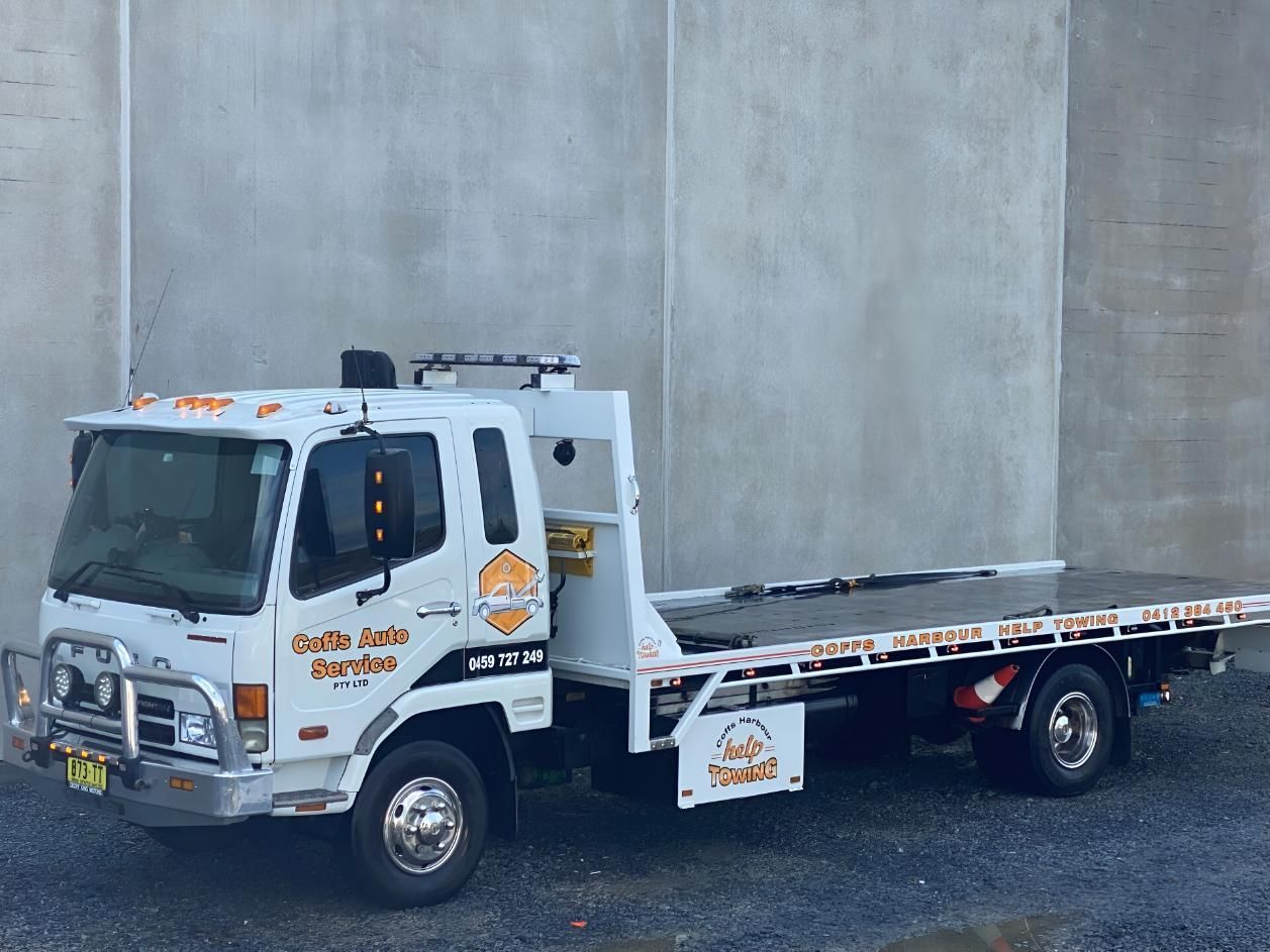 A White Tow Truck is Parked in Front of a Concrete Wall — Coffs Tow Trucks In North Boambee Valley, NSW