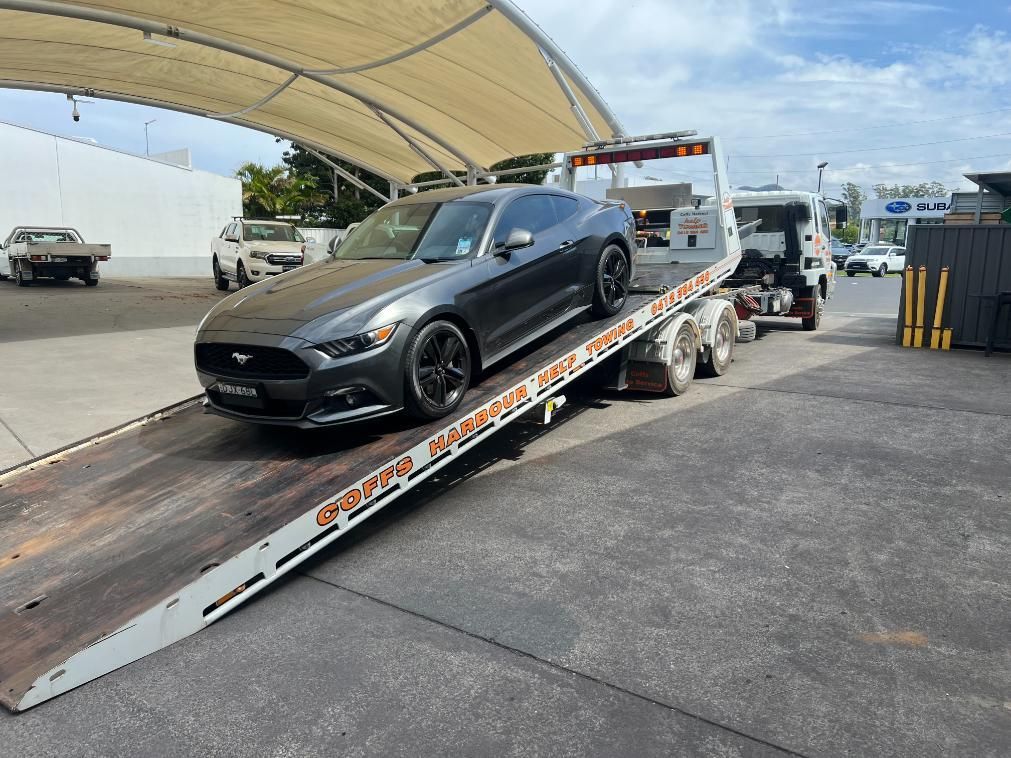A Ford Mustang is Being Towed by a Tow Truck — Coffs Tow Trucks In Sawtell, NSW