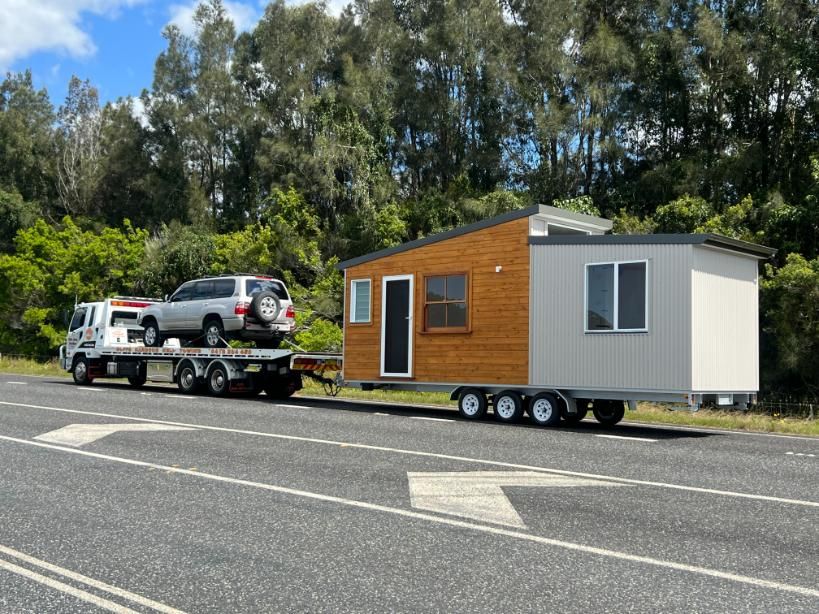 A truck is towing a small house on a trailer — Coffs Tow Trucks In Macksville, NSW