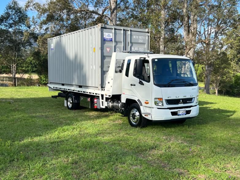 A White Truck With a Container on the Back is Parked in a Grassy Field — Coffs Tow Trucks In Sawtell, NSW