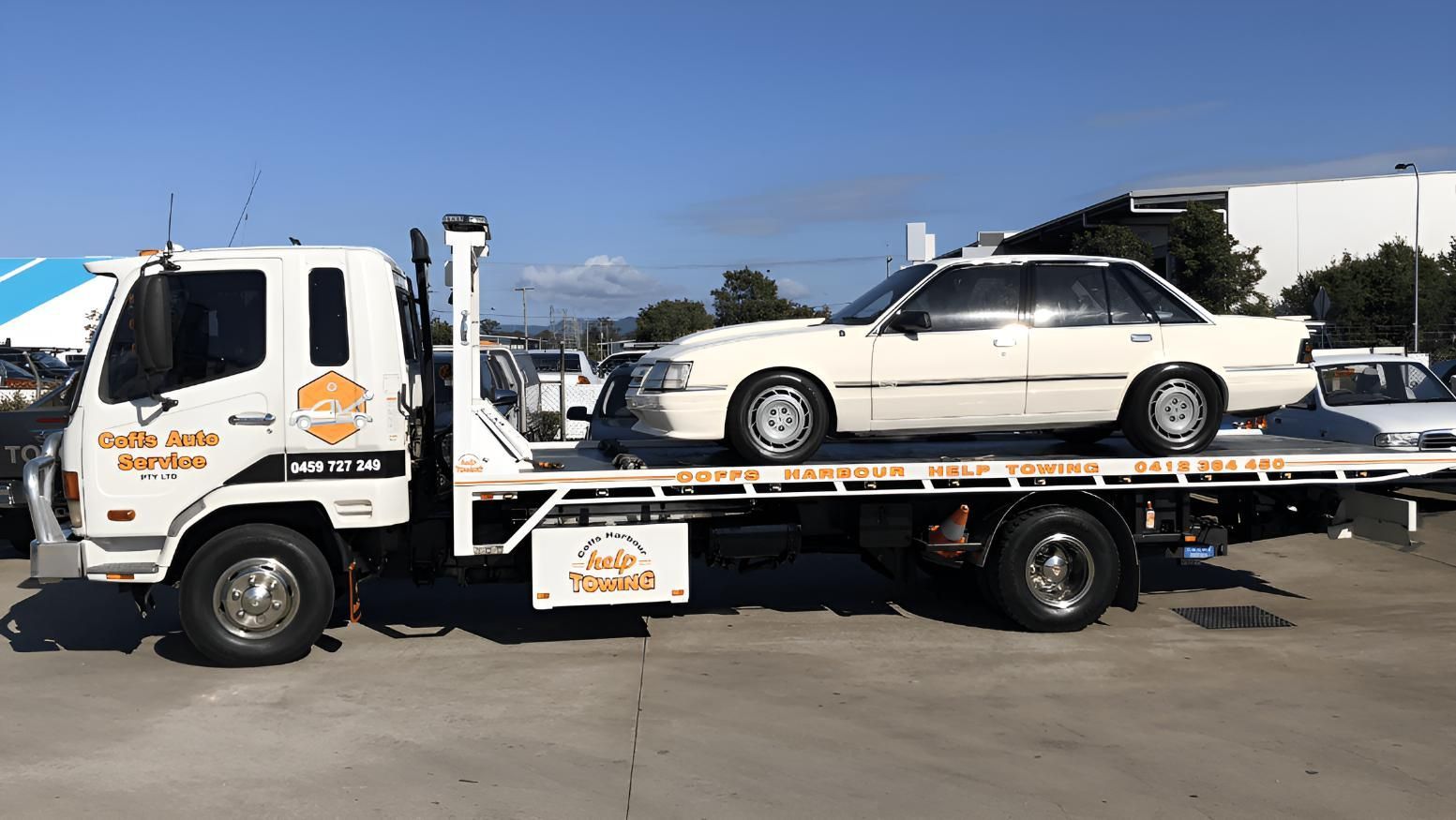 A White Car is Sitting on Top of a Tow Truck — Coffs Tow Trucks In North Boambee Valley, NSW
