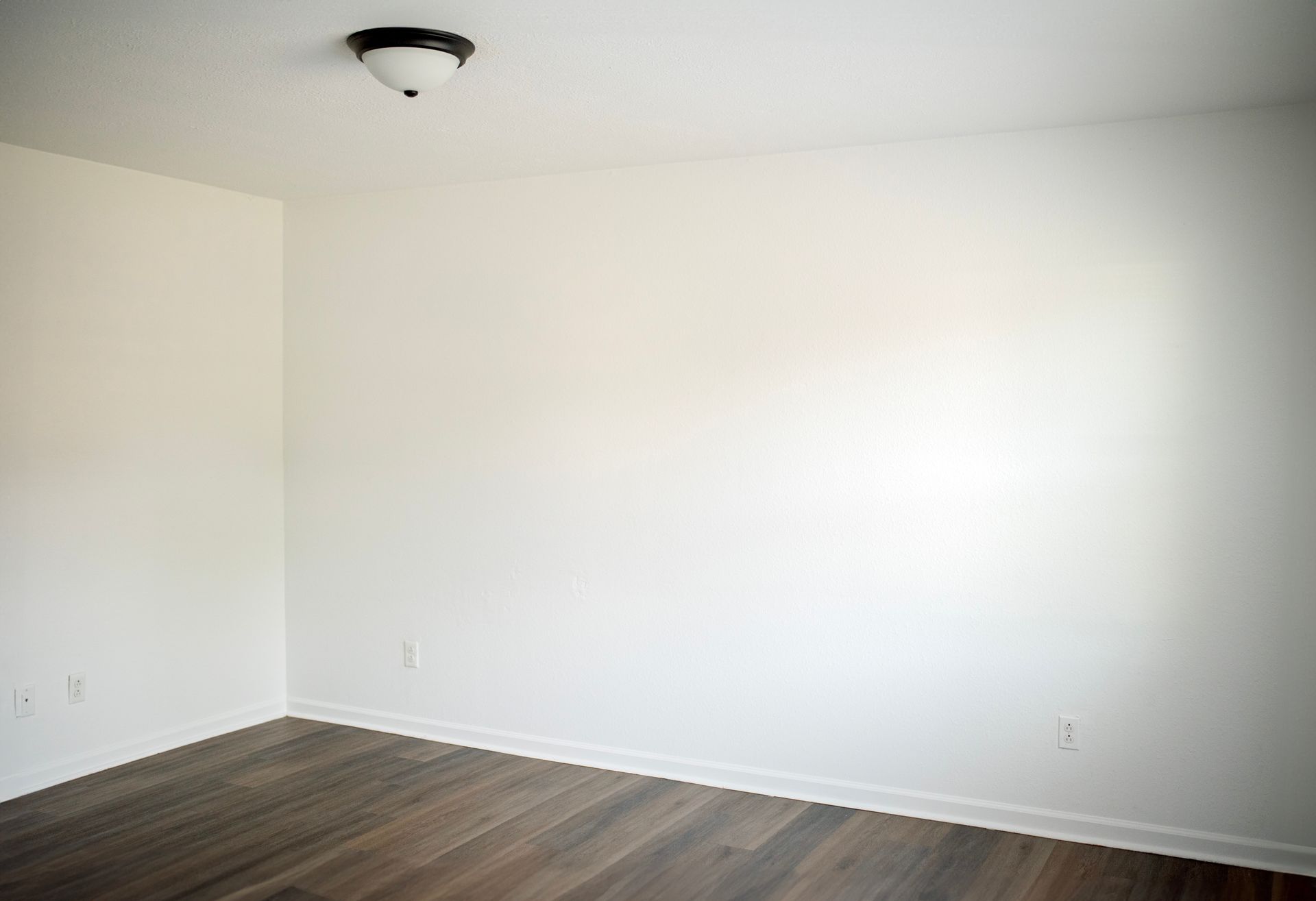 An empty room with white walls and wooden floors.