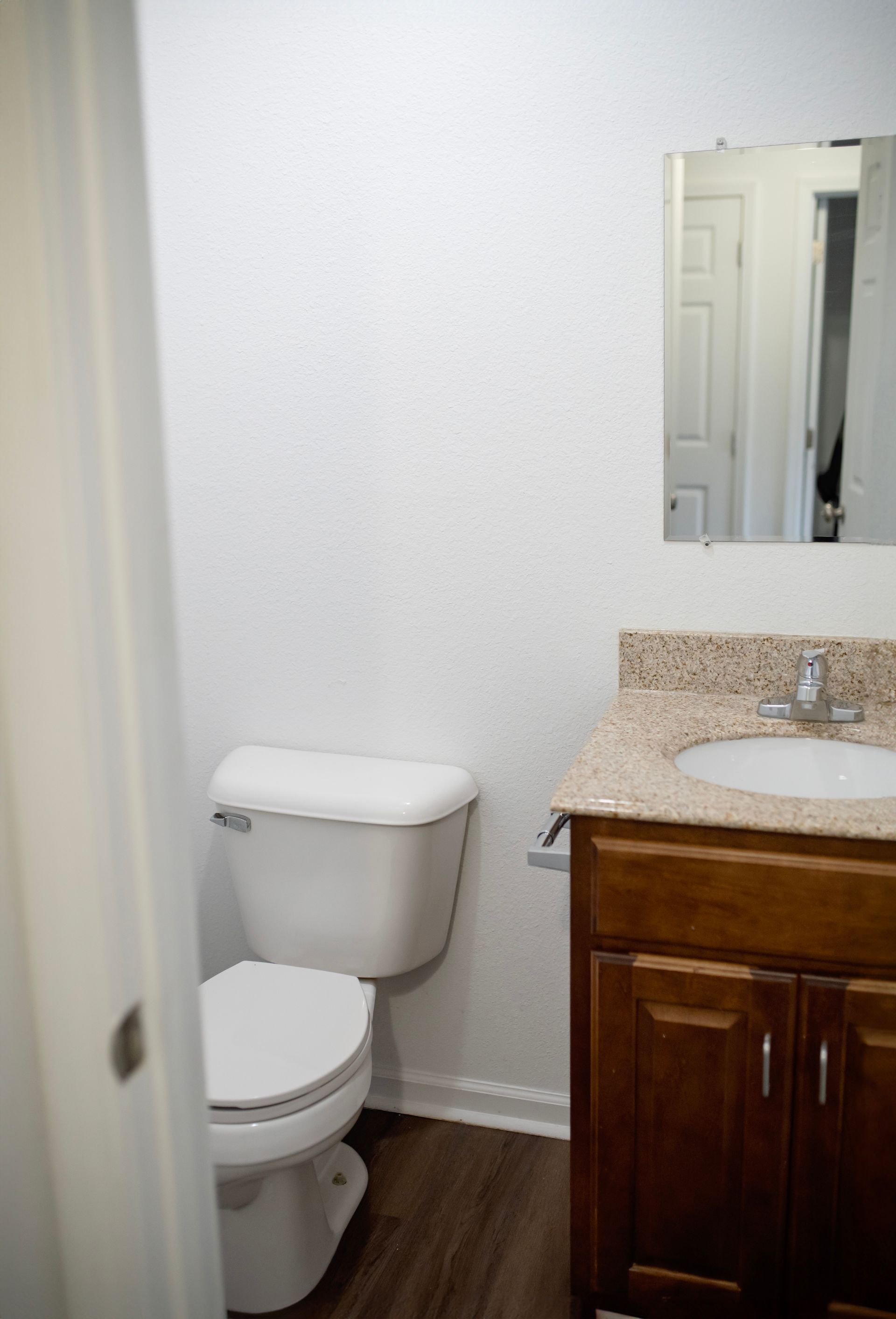 A bathroom with a toilet , sink and mirror.