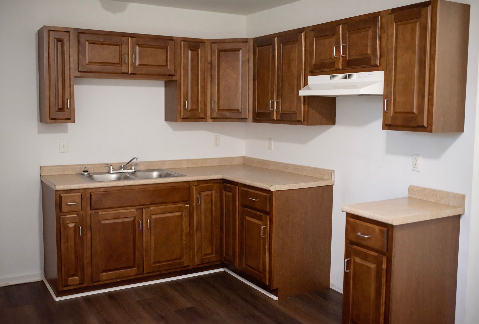 An empty kitchen with wooden cabinets and a sink.